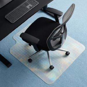 Ergonomic black office chair with mesh back on a wheeled base, placed on a translucent dotted anti-fatigue mat under a desk with a keyboard nearby